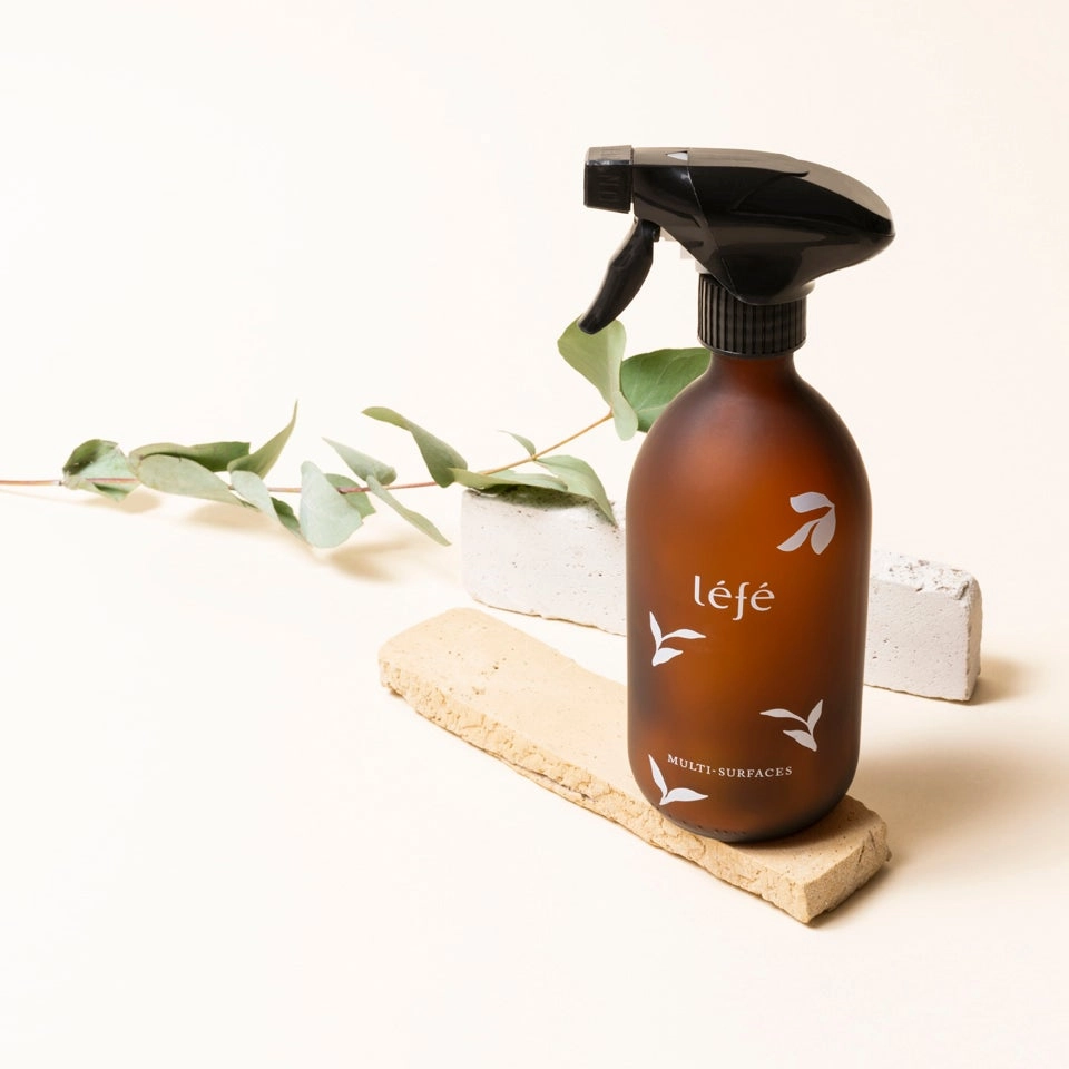 Spray Multi-Surfaces léfé flacon ambré avec pompe, parfum eucalyptus, posé sur une pierre naturelle avec des feuilles d'eucalyptus